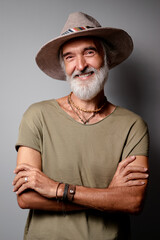 Style and vacation concept. Studio portrait of handsome senior man with gray beard and hat.