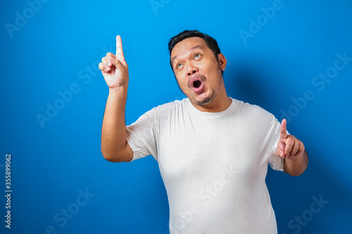 Fotomural Portrait of a funny fat Asian man in white t-shirt smiling and dancing happily,