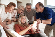 Happy Mature Woman Showing Photos To Her Friends .