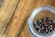 Close up of Roasted coffee beans in a glass jar on wooden table background.
