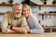 © InsideCreativeHouse - Portrait of middle aged couple hugging while standing together in kitchen at home