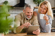 © InsideCreativeHouse - Happy senior couple using digital tablet in kitchen at home