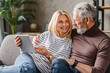 © InsideCreativeHouse - Happy middle aged couple using digital tablet on sofa at home while looking on each other
