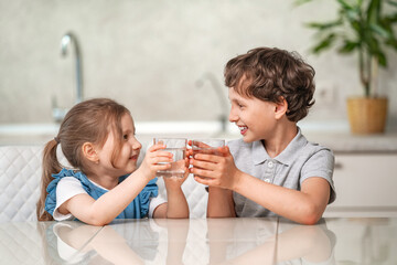 Funny little children drink water in the kitchen at home.