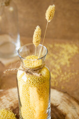 Wall Mural - Millet in a glass jar on a wooden stand, next is an ear of wheat