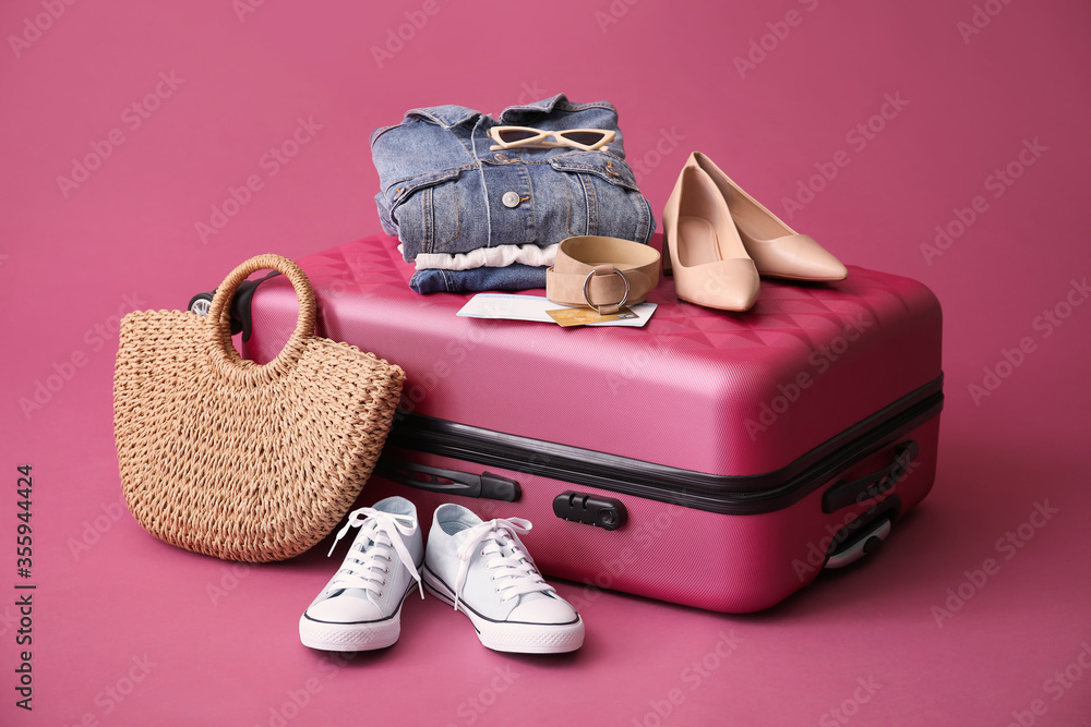 Packed suitcase and accessories on color background
