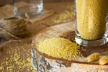 millet in a glass jar on a wooden stand, next is an ear of wheat