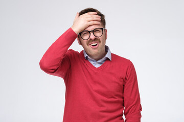 Wall Mural - Feeling exhausted. Young man in red sweater touching his head checking temperature