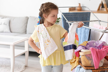 Wall Mural - Little girl with dirty laundry at home