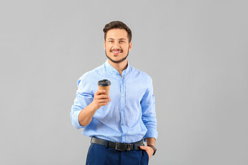 Wall Mural - Handsome young businessman with coffee on grey background