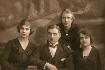 latvia - circa 1920s: group portrait shot of three female and man in studio. vintage carte de viste 