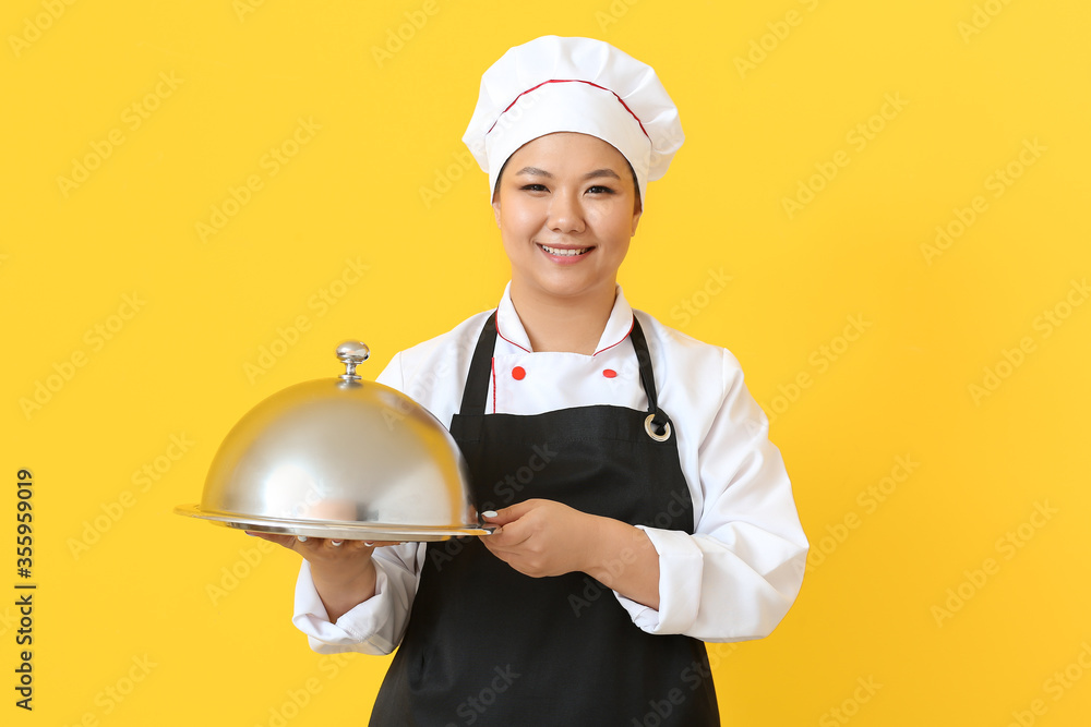 Beautiful Asian chef with tray on color background
