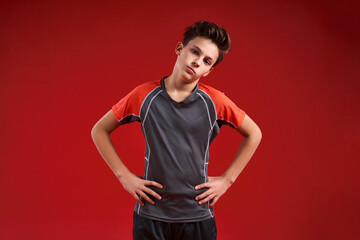 Time to train. A teenage boy is engaged in fitness, he is looking at camera while doing exercise. Isolated on red background. Sport, training, fitness, active lifestyle concept. Horizontal shot