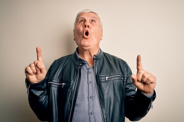 Wall Mural - Senior handsome hoary man wearing casual shirt and jacket over isolated white background amazed and surprised looking up and pointing with fingers and raised arms.