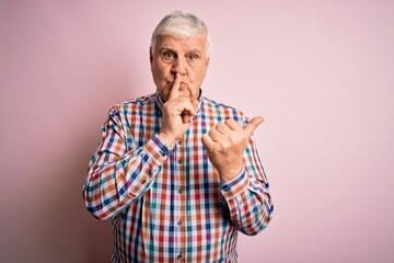 Wall Mural - Senior handsome hoary man wearing casual colorful shirt over isolated pink background asking to be quiet with finger on lips pointing with hand to the side. Silence and secret concept.