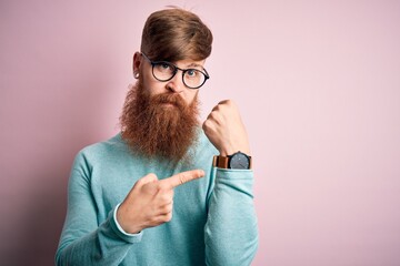 Wall Mural - Handsome Irish redhead man with beard wearing glasses over pink isolated background In hurry pointing to watch time, impatience, looking at the camera with relaxed expression