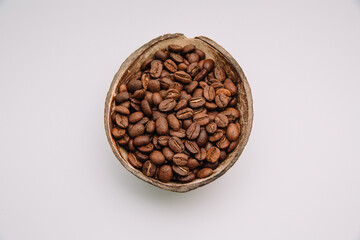 Close up shot of roasted coffee beans in a coconut shell bowl isolated on white background with copy space