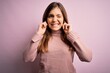© Krakenimages.com - Beautiful young woman wearing turtleneck sweater over pink isolated background covering ears with fingers with annoyed expression for the noise of loud music. Deaf concept.