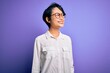 © Krakenimages.com - Young beautiful asian girl wearing casual shirt and glasses standing over purple background looking away to side with smile on face, natural expression. Laughing confident.