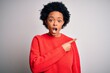 © Krakenimages.com - Young beautiful African American afro woman with curly hair wearing red casual sweater Surprised pointing with finger to the side, open mouth amazed expression.