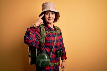 Poster - Middle age curly hair hiker woman hiking wearing backpack and water canteen using binoculars Smiling pointing to head with one finger, great idea or thought, good memory