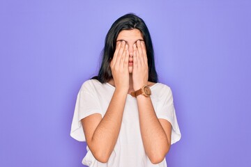 Poster - Young beautiful brunette woman wearing casual white t-shirt over purple background rubbing eyes for fatigue and headache, sleepy and tired expression. Vision problem