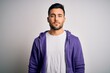Young handsome man wearing purple sweatshirt standing over isolated white background with serious expression on face. Simple and natural looking at the camera.