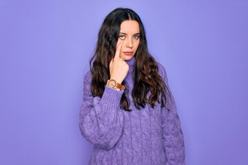 Wall Mural - Young beautiful woman wearing casual turtleneck sweater standing over purple background Pointing to the eye watching you gesture, suspicious expression