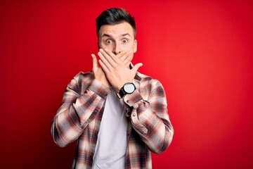 Wall Mural - Young handsome caucasian man wearing casual modern shirt over red isolated background shocked covering mouth with hands for mistake. Secret concept.