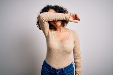 Poster - Young beautiful curly arab woman wearing casual t-shirt and glasses over white background covering eyes with arm, looking serious and sad. Sightless, hiding and rejection concept