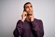 © Krakenimages.com - Young handsome african american man having conversation talking on the smartphone serious face thinking about question, very confused idea