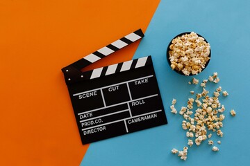 Filmmaking concept. Movie Clapperboard. Cinema begins with movie clappers. Movie clapper on an orange and a blue background and popcorn.