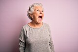 Fototapeta  - Senior beautiful woman wearing casual t-shirt standing over isolated pink background angry and mad screaming frustrated and furious, shouting with anger. Rage and aggressive concept.