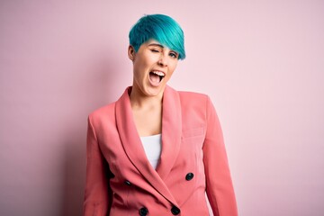 Sticker - Young beautiful businesswoman with blue fashion hair wearing jacket over pink background winking looking at the camera with sexy expression, cheerful and happy face.