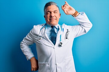 Poster - Middle age handsome grey-haired doctor man wearing coat and blue stethoscope stretching back, tired and relaxed, sleepy and yawning for early morning