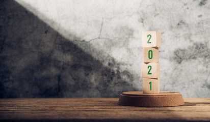 Poster - 2021 happy new year on wood block on wood table and concrete wall with sunlight from window.hope new year concept