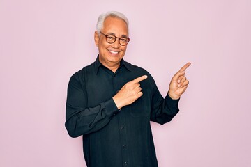 Poster - Middle age senior grey-haired handsome man wearing glasses and elegant shirt smiling and looking at the camera pointing with two hands and fingers to the side.