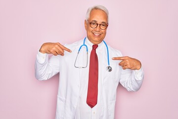 Canvas Print - Middle age senior grey-haired doctor man wearing stethoscope and professional medical coat looking confident with smile on face, pointing oneself with fingers proud and happy.