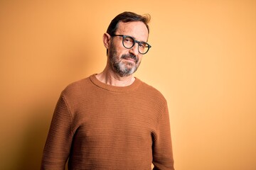 Poster - Middle age hoary man wearing brown sweater and glasses over isolated yellow background looking sleepy and tired, exhausted for fatigue and hangover, lazy eyes in the morning.