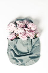 Wall Mural - blue cotton eco tote bag with peony flowers on white background, flat lay
