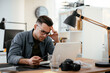 © JustLife - Young businessman using laptop in his office. Businessman working and taking notes.