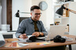 © JustLife - Young businessman using laptop in his office. Businessman working and taking notes.