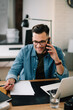 © JustLife - Businessman in office. Handsome man talking on phone at work.