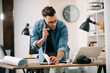 © JustLife - Businessman in office. Handsome man talking on phone at work.
