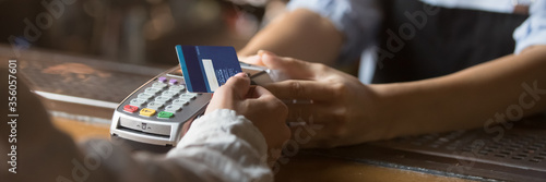 Fotomural Customer stand near bar counter make payment use contactless credit card close up hands device view, cashless method pay bills in commercial places concept
