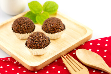 Wall Mural - Perilla seeds mixed with jaggery and molded into cubes, placed on foil and a wooden plate decorated with mint leaves and spoons and forks.