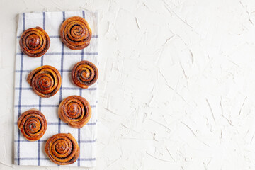 Wall Mural - baked cinnamon buns on light background with checkered napkin