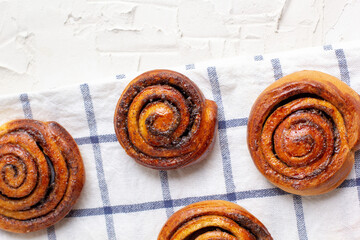 Wall Mural - baked cinnamon buns on light background with checkered napkin