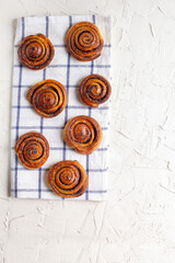 Wall Mural - baked cinnamon buns on light background with checkered napkin