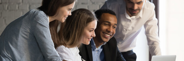 Horizontal photo banner for website header design, diverse employees gathered in office having fun watching funny video, discussing new ideas, brainstorming using laptop enjoy break in workday concept